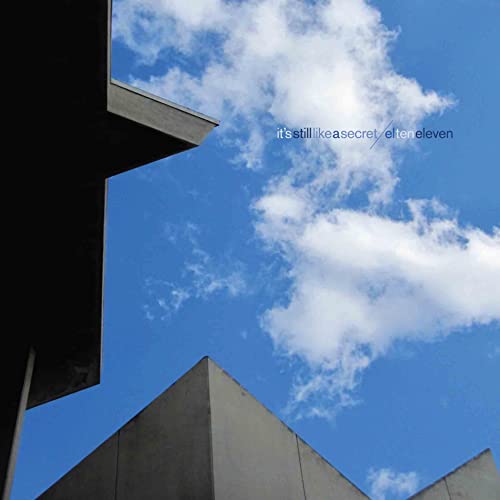 Low-angle view of modern concrete buildings against a bright blue sky with clouds.