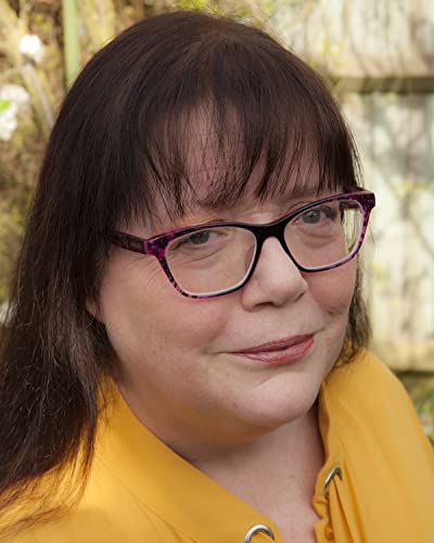 Close-up of a woman with glasses and dark hair, wearing yellow.