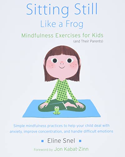 A young girl sits cross-legged on a blue mat with a small frog beside her.