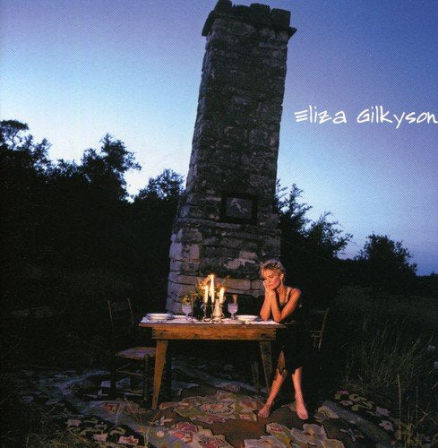 "Album cover with a woman sitting at a candlelit table beside a stone chimney."