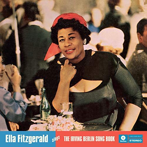 Ella Fitzgerald wearing a red headscarf, sitting at a table in a crowded room.