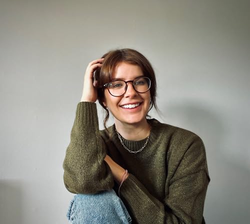Smiling woman with glasses and olive green sweater, author portrait.