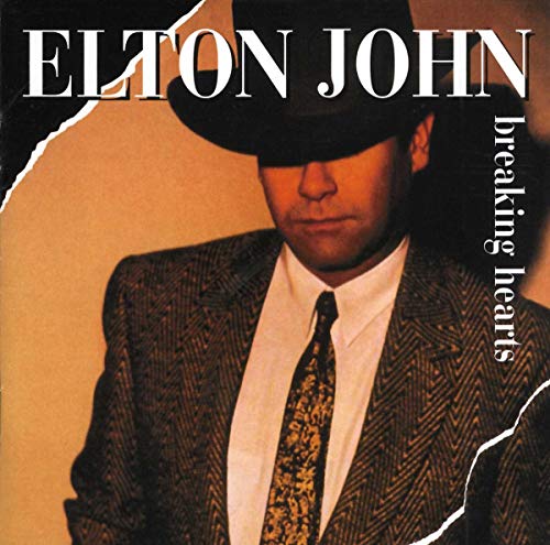 Elton John in a hat and suit, album cover for "Breaking Hearts.