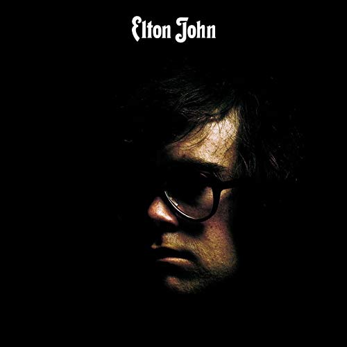 Elton John album cover: close-up portrait in shadow, wearing glasses.