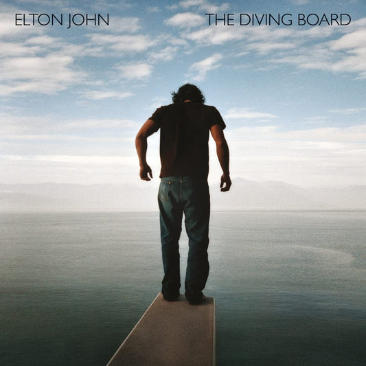 Man standing on a diving board overlooking a blue ocean and sky.