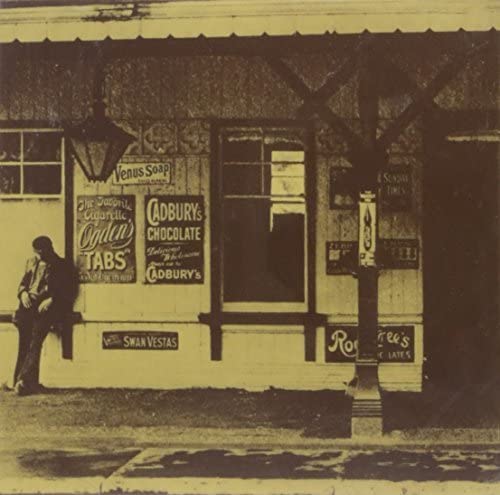 Sepia-toned album cover with a vintage storefront and a figure standing nearby.