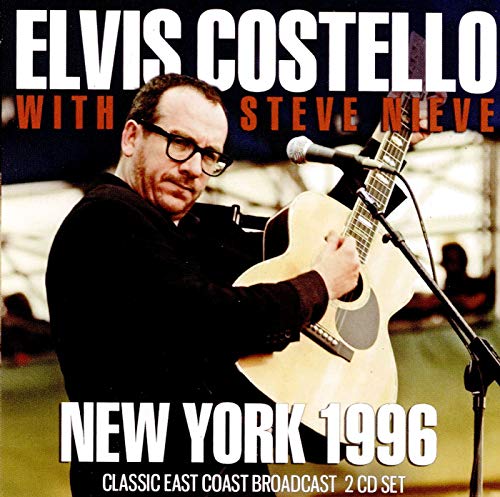 Elvis Costello playing an acoustic guitar on stage with text overlay.