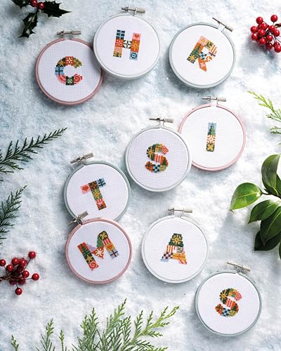 Seven cross-stitch hoops spelling “MERRY” and “STITCHMAS” on a snowy surface.