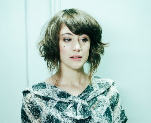 Portrait of a woman with wavy brown hair, looking forward.