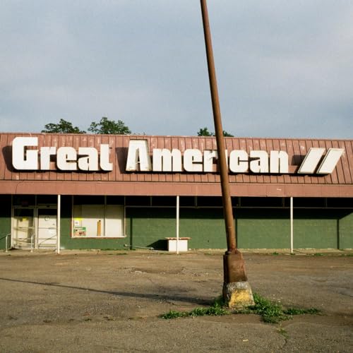 A weathered Great American store front with a tall pole in the foreground.