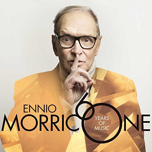 Ennio Morricone with glasses holding a finger to his lips, wearing a gold jacket.