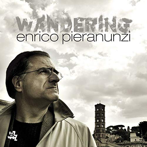 "Album cover featuring a man in a jacket with a cloudy sky background."