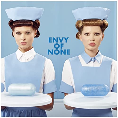 Two women dressed as nurses hold trays with blue capsules against a blue background.