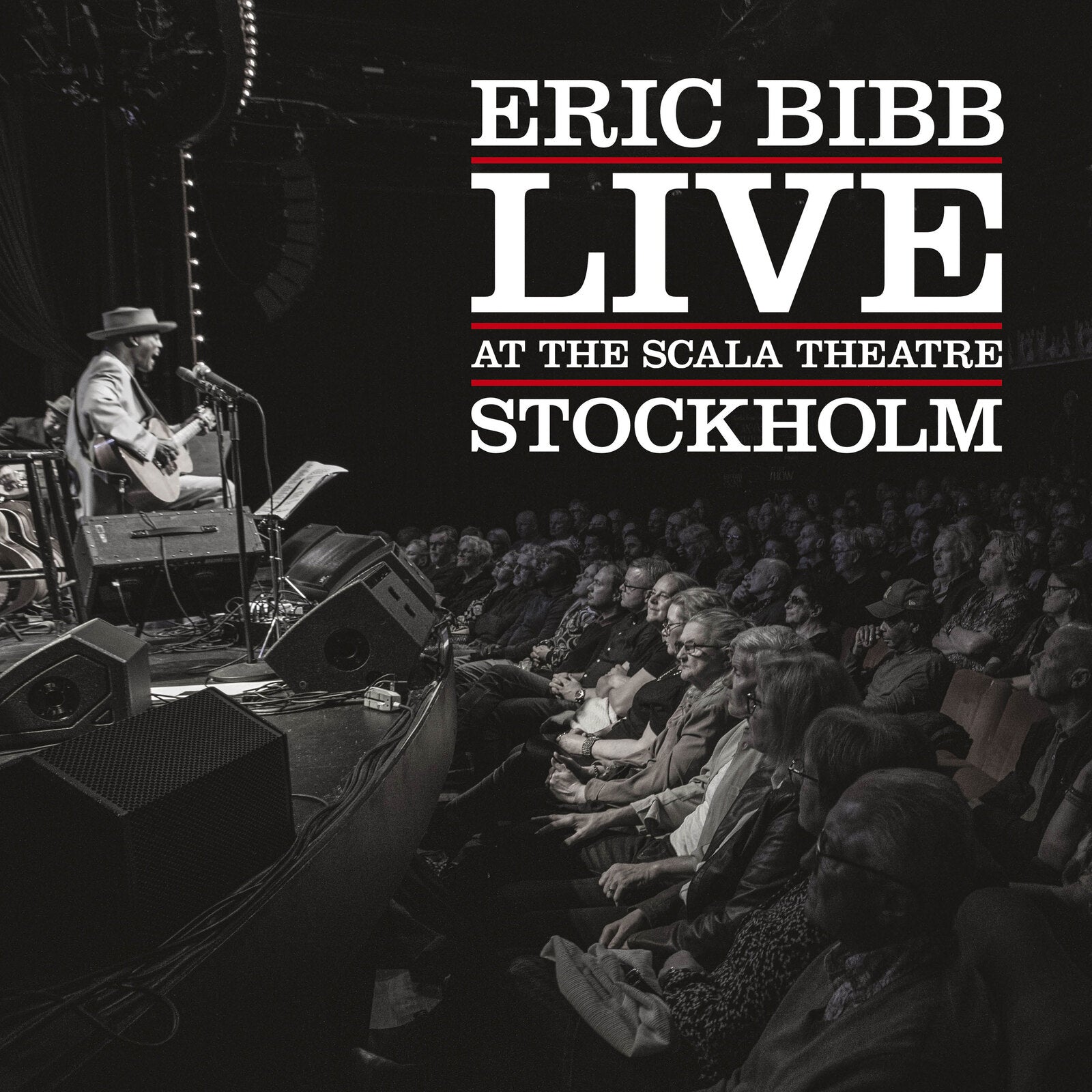 Eric Bibb performing live on stage with an audience in Stockholm.