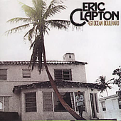 Eric Clapton album cover: palm tree, building, and a person standing outside.