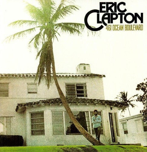 "Eric Clapton album cover featuring a man standing outside a white house with a palm tree."