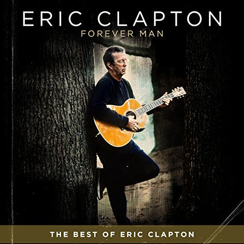 Eric Clapton holding an acoustic guitar, standing between trees.