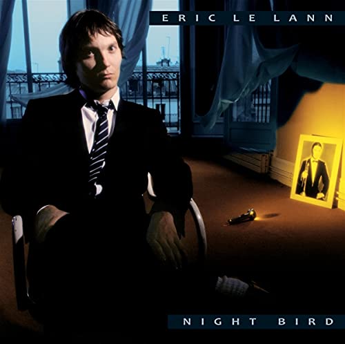 Eric Le Lann in a suit sits in a room with a framed photo.