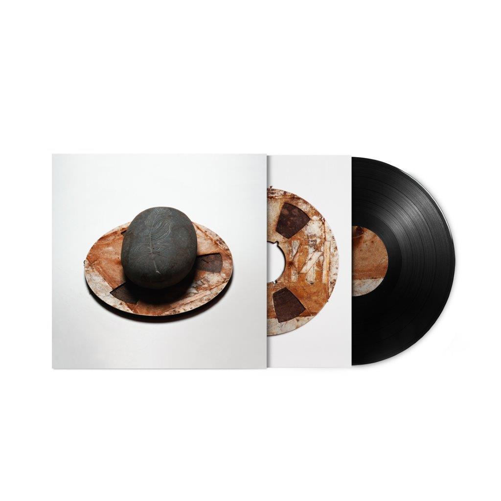 Vinyl record and album cover featuring stones on a patterned surface.