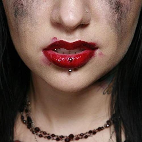 Close-up of a person with smudged makeup, red lipstick, and a lip piercing.