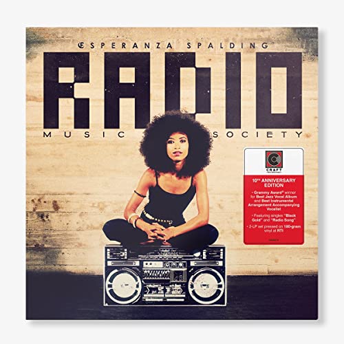 Woman with afro sits on boombox in front of wood wall with text overlay.