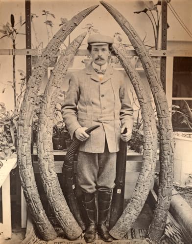 Vintage photo of a man standing between two carved elephant tusks.