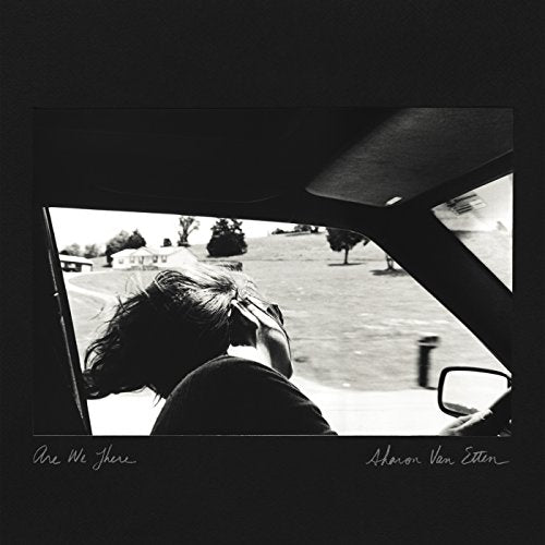Black and white album cover showing a person viewed from inside a car.