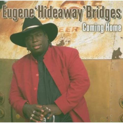 Eugene Hideaway Bridges wearing a black cowboy hat and red jacket in front of metal.