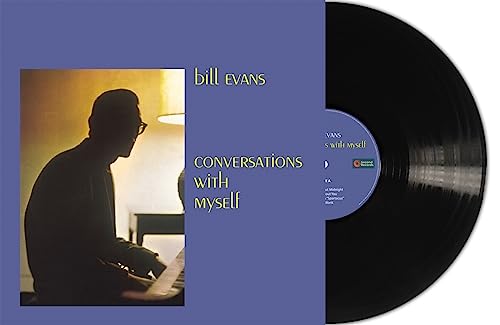 A black vinyl record partially tucked into a purple album cover featuring Bill Evans.