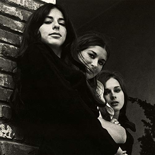 Black and white portrait of three young women against a brick wall.