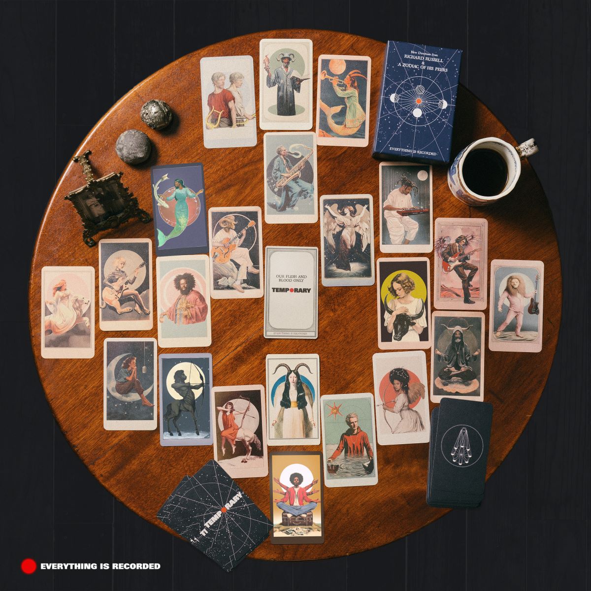 Vinyl record artwork surrounded by tarot cards and small objects on wood.