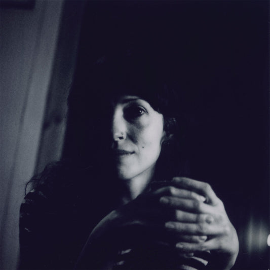 Black and white portrait of a woman with hands clasped near her chest.