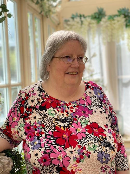 Smiling woman with glasses wearing a colorful floral print dress.