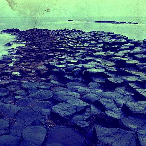 Hexagonal basalt columns extend toward a blue ocean and sky.