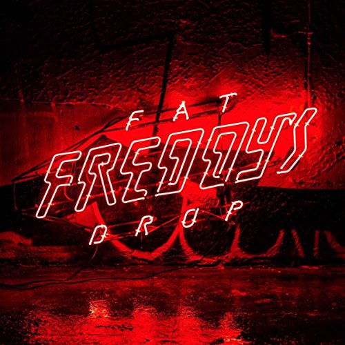 Red neon sign spelling “Fat Freddy’s Drop” against a dark, blurred background.