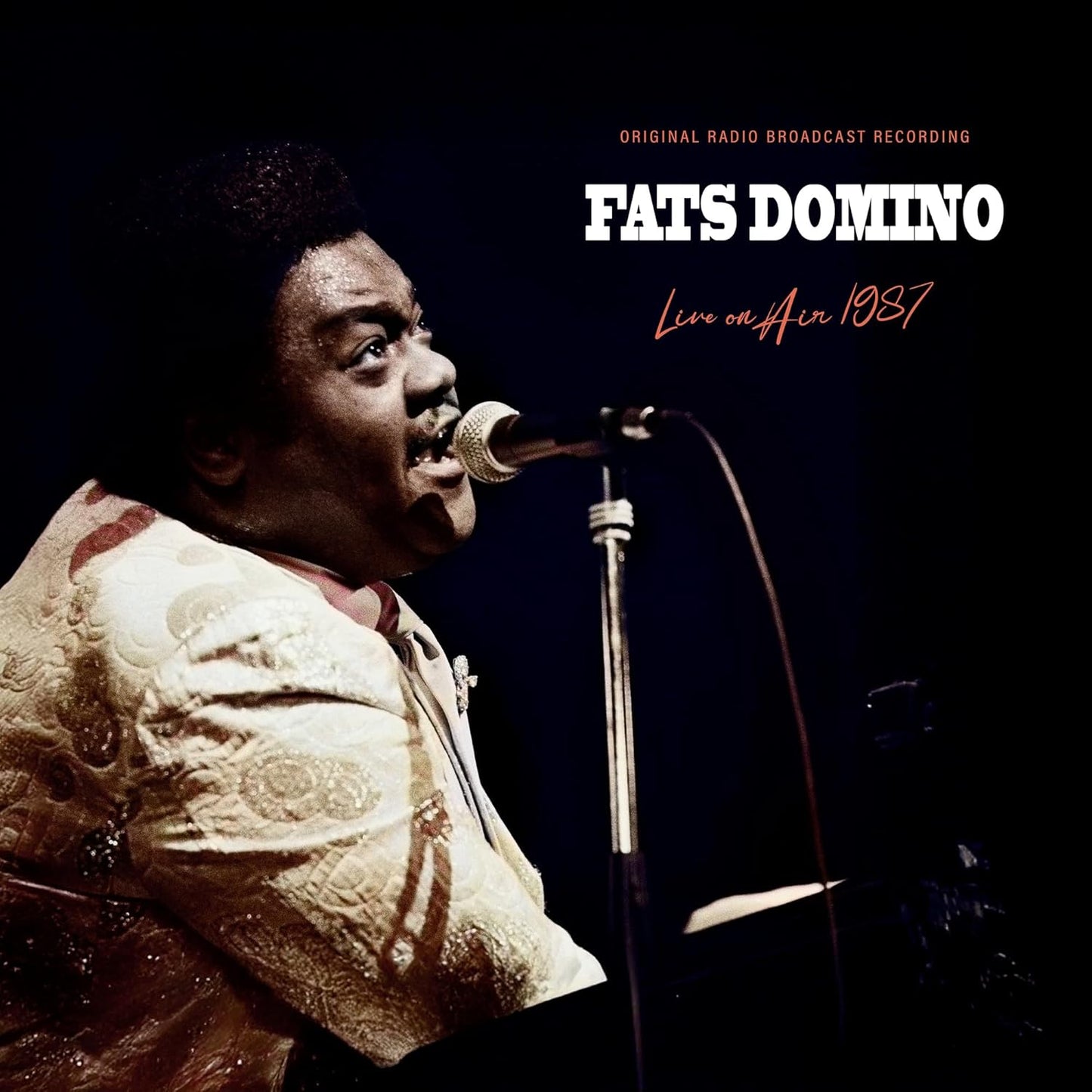 Fats Domino singing into a microphone on the cover of his 1987 live album.