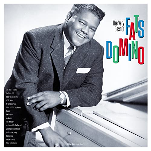 Black and white photo of Fats Domino smiling next to a piano.