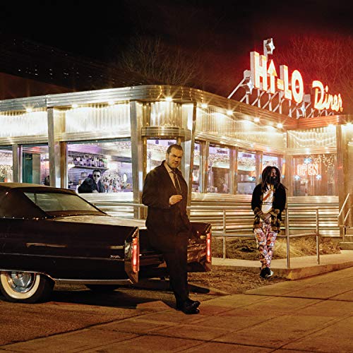 Two men stand outside a retro Hi-Lo Diner at night next to a car.