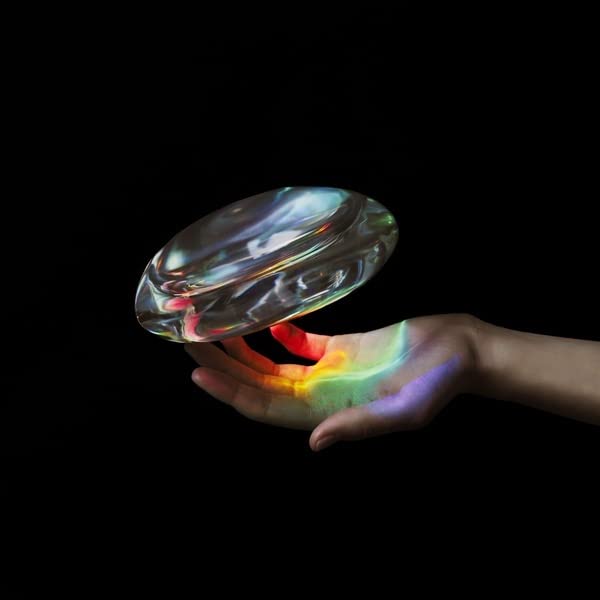 Hand holding a translucent vinyl record with rainbow light effects.