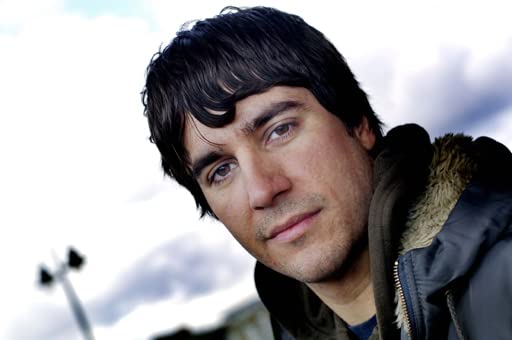 Close-up of a man with dark hair wearing a hooded jacket.