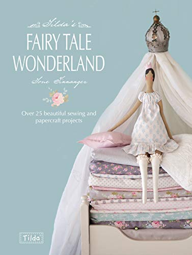 A cloth doll wearing a crown sits on a stack of patterned fabric quilts.