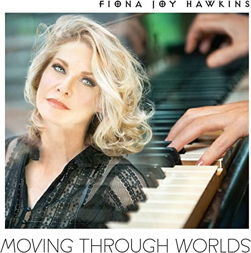 Fiona Joy Hawkins looking at the camera with hands playing a grand piano.
