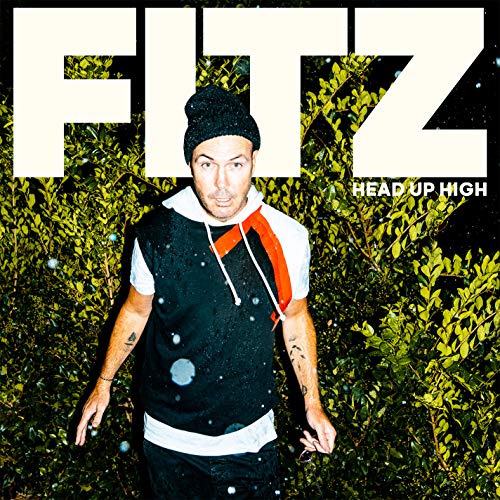 Man standing in front of a leafy green background, wearing a beanie and hoodie.