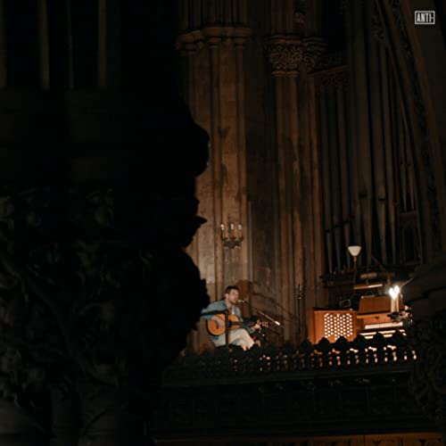 Man playing guitar in a dimly lit, ornate church interior.