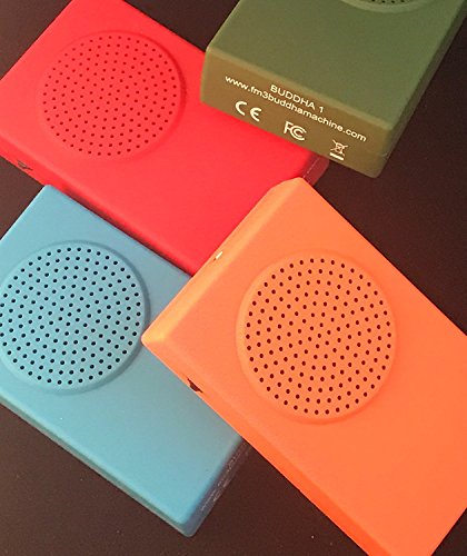 Four colorful FM3 Buddha Machine music players arranged on a dark surface.