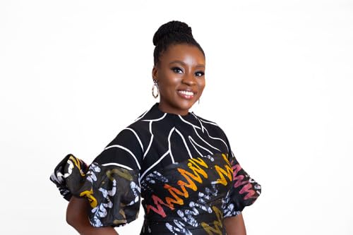 A smiling Black woman with hair in a bun wears a patterned black dress.