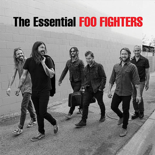 The Foo Fighters band members walking together in front of a concrete block wall.