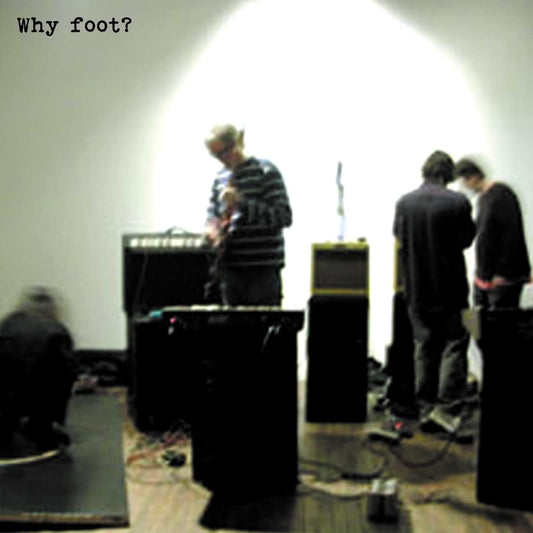 Blurry image of musicians performing with equipment on a wooden floor.