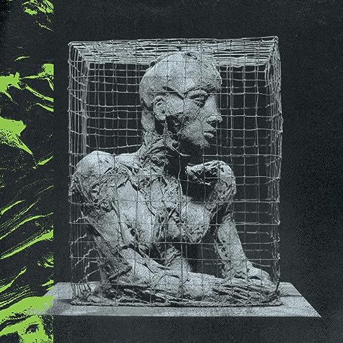 Sculptural head in a wire cage, with green paint splatters on black.