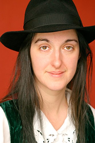 Woman with long dark hair wearing a black hat and green vest.